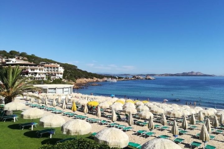 Piesková pláž s ležadlami a slnečníkmi pred hotelom Club Hotel Baja Sardinia